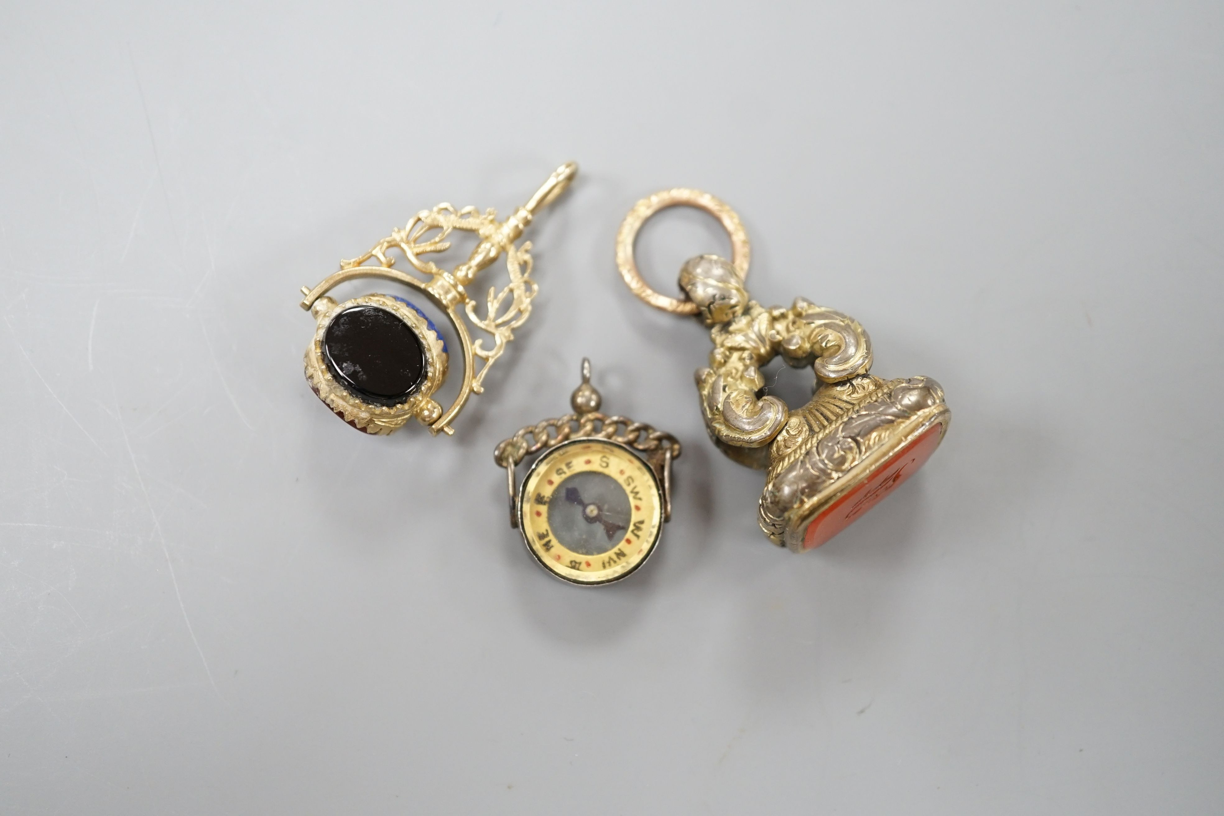 A modern 9ct gold and carnelian set swivelling fob seal, 40mm, a Victorian gold plated and carnelian set fob seal and a white metal mounted (stamped silver) compass fob.